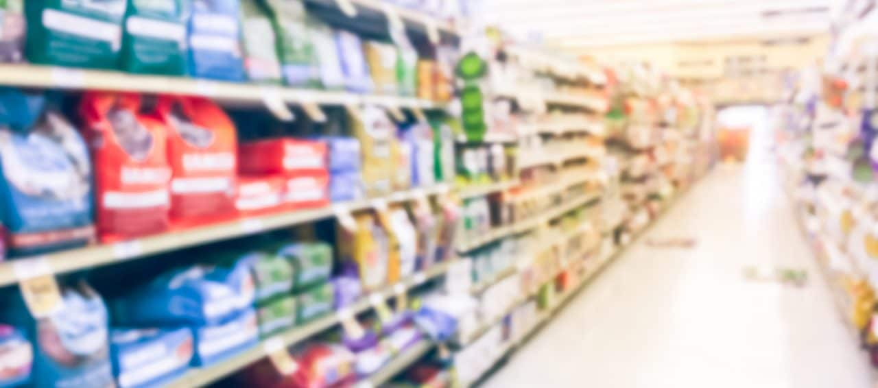 Vintage blurred abstract dog and cat food shelves at retail store in America. Defocused pet supplies, laundry, dish soap, cat litter aisle row.