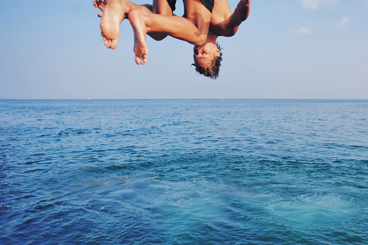 Young man jumping off cliff into blue water ocean at sunset. Active outdoor, holiday adventure, tourism action, healthy summer joy, Fun activity lifestyle. Crazy adult guy in swimwear fly from climb; Shutterstock ID 1426920497; purchase_order: -; job: -; client: -; other: -
