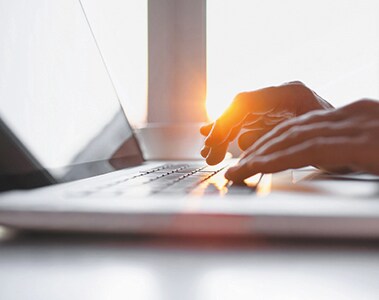 Close-up of male hands typing on laptop keyboard