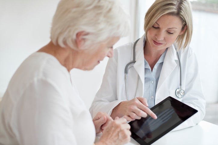 MODEL RELEASED. Female doctor showing senior patient xray of hand on digital tablet.