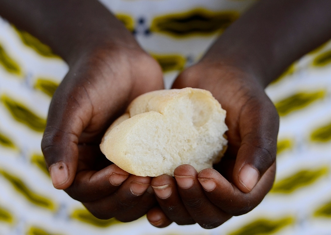Starving Hunger Symbol. Black African girl holding bread to as a malnutrition symbol. It is important to get food and life-saving aid to the worldâ  s most vulnerable people and countries. Stop hunger in the world!