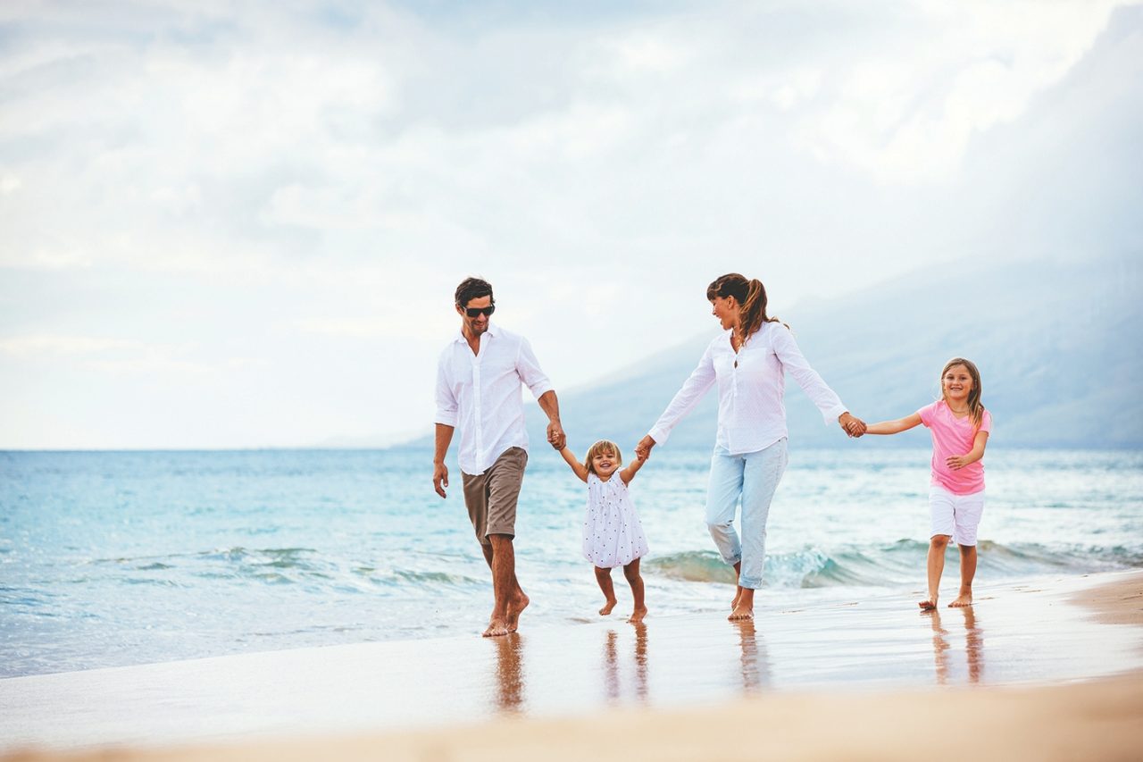 Happy young family walking on the beach at sunset. Happy Family Lifestyle