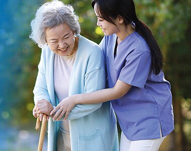 Happy elderly woman walking with the help of a nurse.  