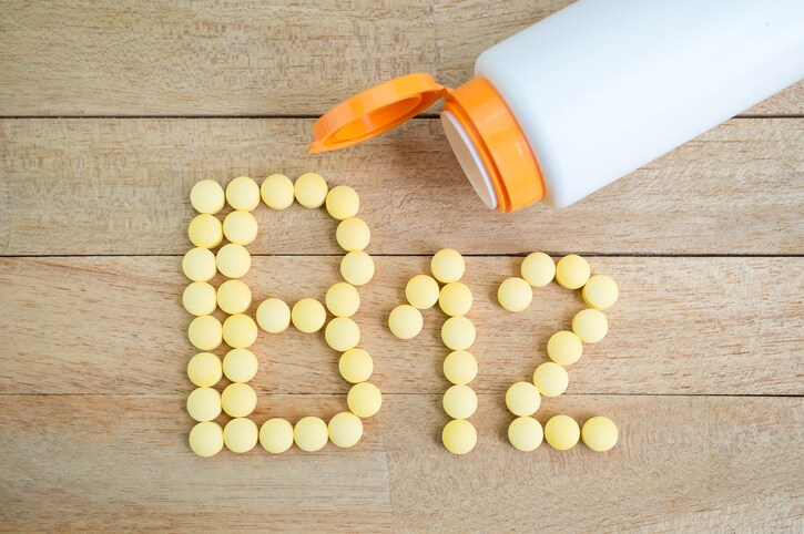 Yellow pills forming shape to B12 alphabet on wood background