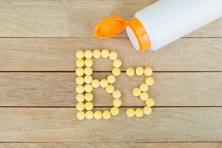Yellow pills forming shape to B3 alphabet on wood background