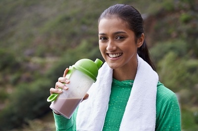 A young ethnic woman drinking a sports drink outdoors