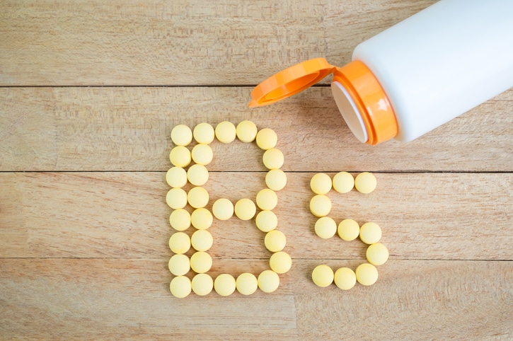Yellow pills forming shape to B5 alphabet on wood background