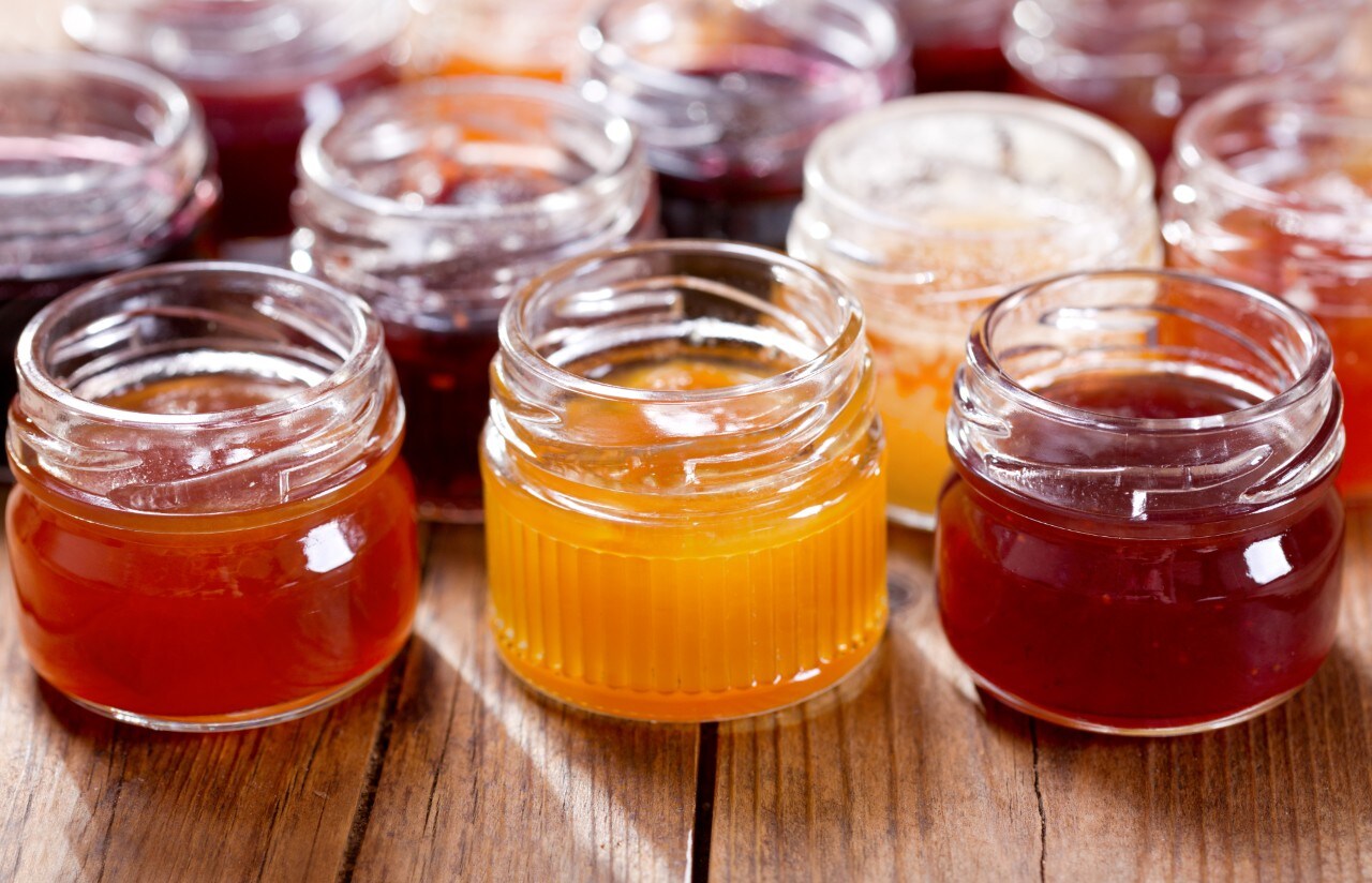 various jars of fruit jam on wooden table