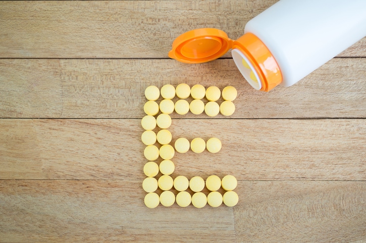 Yellow pills forming shape to E alphabet on wood background