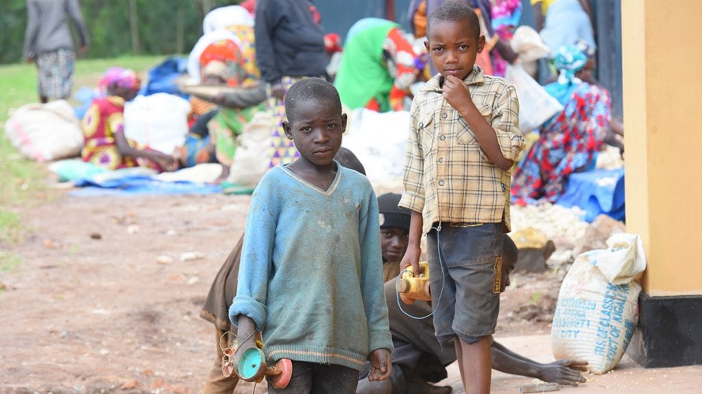 Foto de dos niños con una comunidad humilde al fondo.
