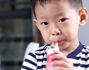 Foto de un niño tomando un líquido del interior de una botella.