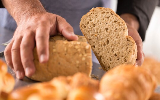 Foto de duas mãos segurando dois pedaços de pão.