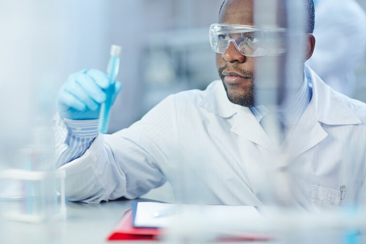 Foto de um cientista, em um laboratório, segurando um tubo de ensaio.