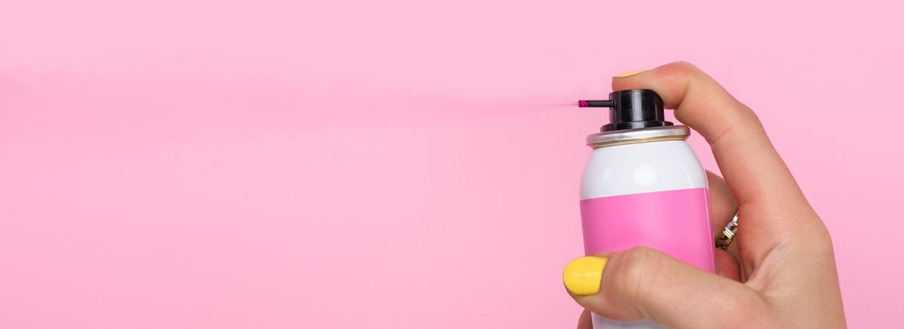 cropped shot of woman with yellow nails holding spray paint for hair isolated on pink