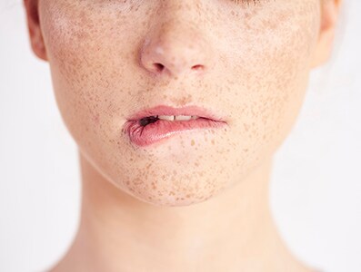 Part of woman biting her lip at studio shot